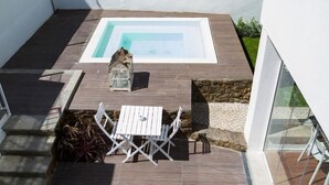 Un patio en la azotea con piscina, una mesa pequeña con sillas y un farol.
