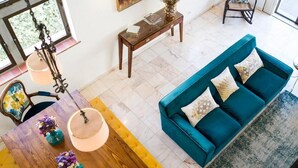 Una sala de estar con un sofá color turquesa, una mesa de centro de madera y una mesa de comedor con sillas.