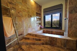 A bathroom with marble walls, a bathtub, and a window with a view of trees. - 3 BDR Private Pool Villa • 8 min to Ao Nang Beach (Ao Nang)