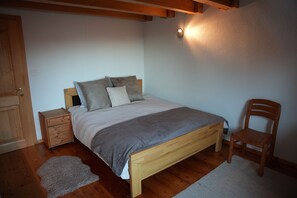 A bedroom with a wooden bed, a nightstand, a chair, and a small rug. - Chalet La Marendaz in Ovronnaz (Ovronnaz)