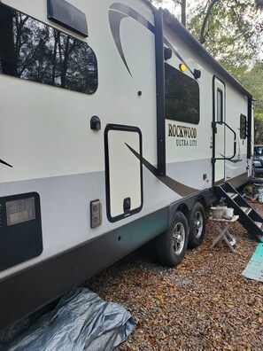 Una caravana Rockwood ULTRA LITE estacionada al aire libre, con un toldo y una rampa que conduce a la entrada.