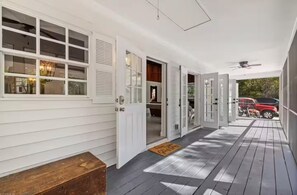 Un portico coperto con rivestimento bianco, una panchina e vista su un veicolo rosso all'esterno.