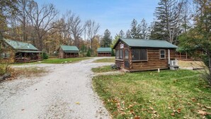 A rustic cabin-style lodging area with multiple cabins, a gravel path, and surrounding trees.