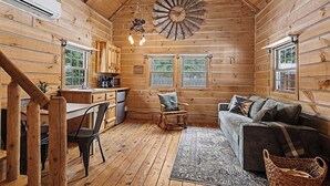A log cabin interior with a dining area, kitchen, and living room.
