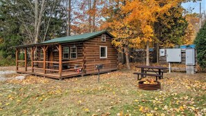 A rustic cabin with a porch, a picnic table, and a fire pit. - The Hideout Cabin | Firepit | Nature | Dunes (Sawyer)