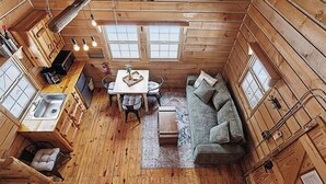 Una habitación tipo cabaña, compacta, con kitchenette, comedor y sofá.