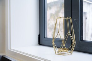 Ein geometrisches, goldfarbenes Objekt auf einer weißen Fensterbank.