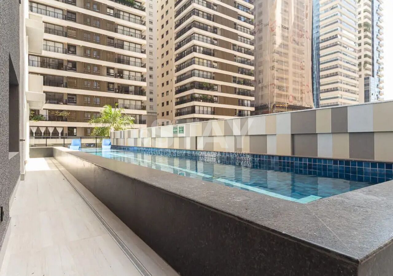 Une piscine dont le bord est recouvert de carreaux, entourée d’immeubles de grande hauteur.