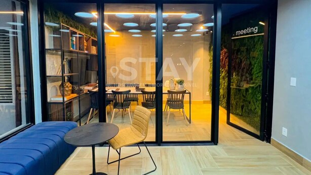 Een modern interieur met een vergaderruimte, een zithoek met een tafel en stoelen, en een glazen wand met een bordje 'meeting'.