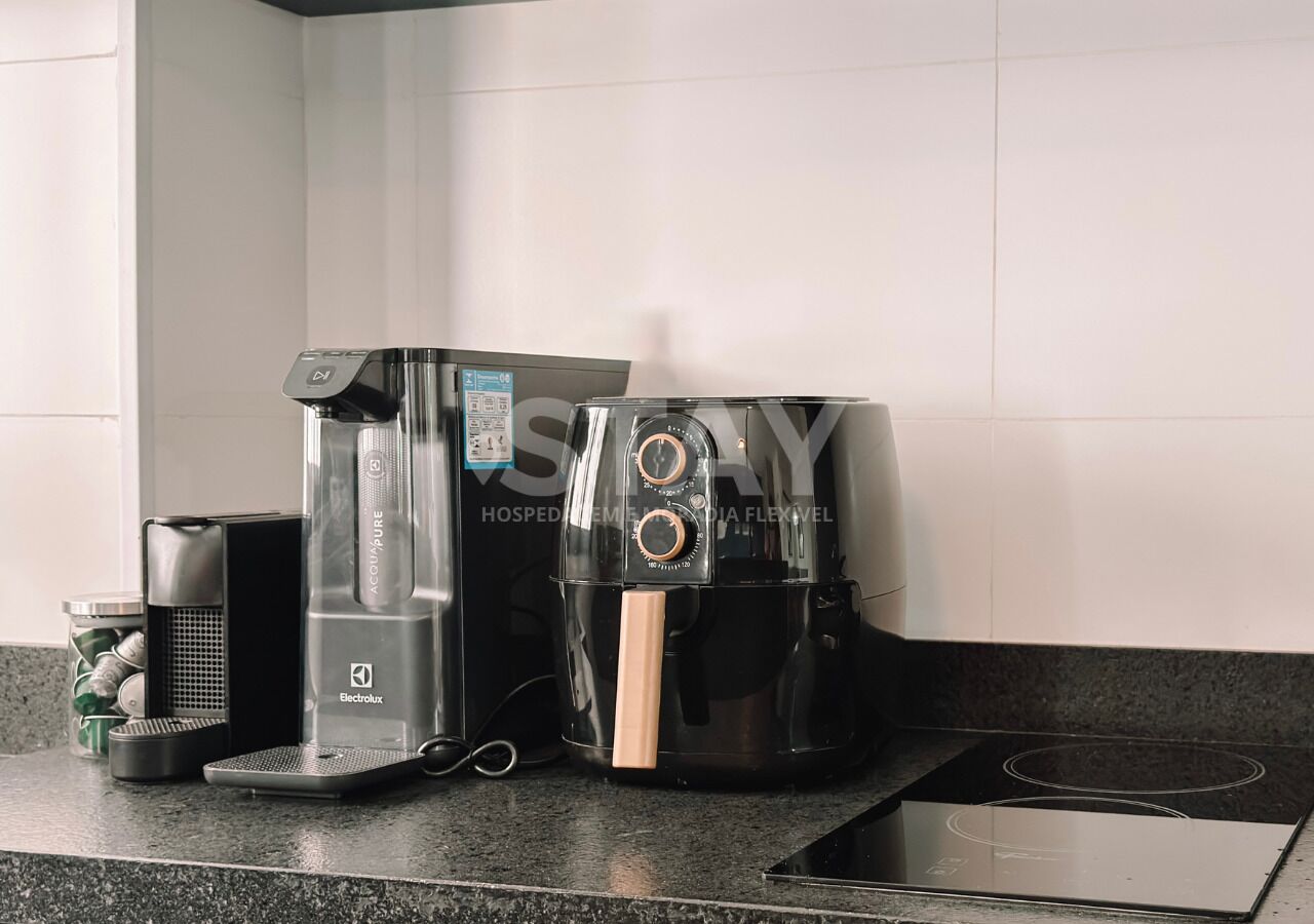 A kitchen with a coffee maker, a scale, and a kettle.