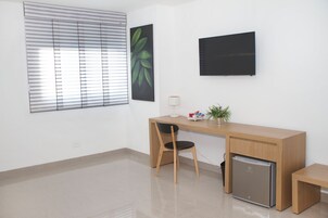 Un espacio de oficina moderno con un escritorio, una silla y un refrigerador pequeño.