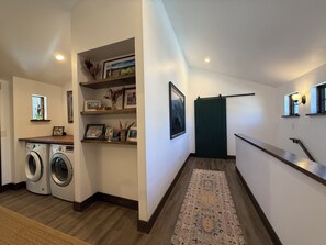 A laundry area with a washing machine and dryer, a wooden bench, a rug, and a green door. - 3BR Farmhouse in Durango with Fitness Room, Sauna, Bidets, Theater Entertainment (Durango)