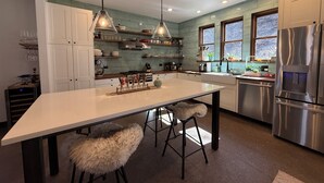 A modern kitchen with a central island, pendant lighting, stainless steel appliances, and a view of the outdoors through large windows. - 3BR Farmhouse in Durango with Fitness Room, Sauna, Bidets, Theater Entertainment (Durango)