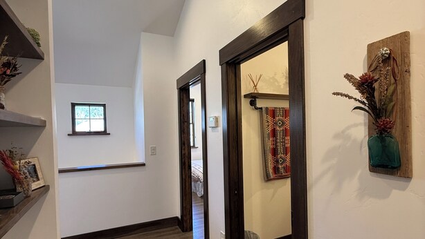A hallway with wooden flooring, a rug, a wooden door frame, a wall-mounted shelf with a vase, and a small window. - 3BR Farmhouse in Durango with Fitness Room, Sauna, Bidets, Theater Entertainment (Durango)