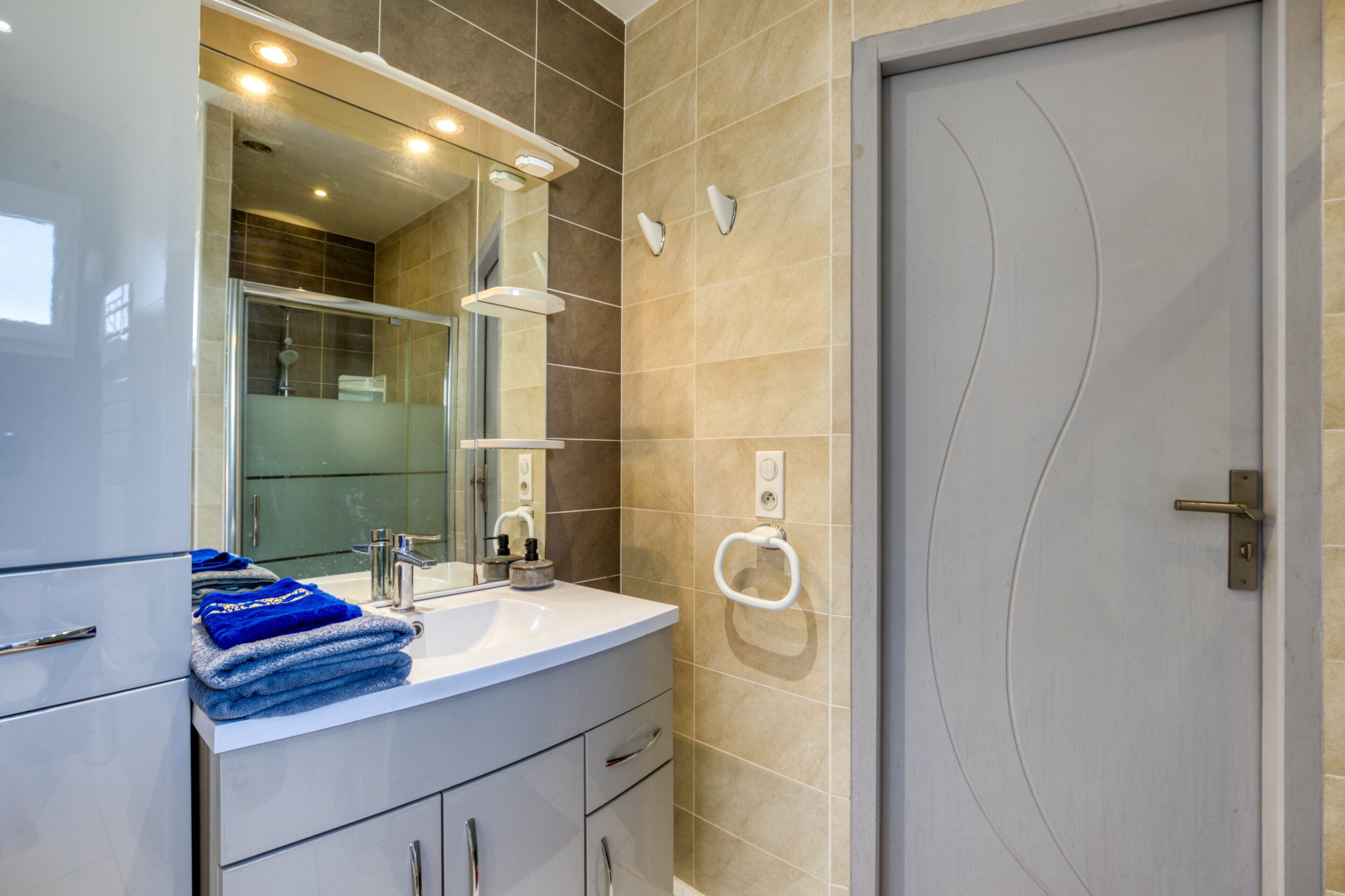 A modern bathroom with a sink, mirror, and towel rack.