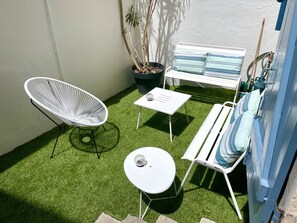 A patio area with a white chair, a small table, a bench with striped cushions, and a potted plant. - Apartment & studio hypercentre terrace Parking (Biarritz)