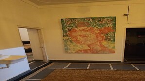 Een kamer met een groot abstract schilderij aan de muur, een receptiebalie en een kamerbreed tapijt met dessin.