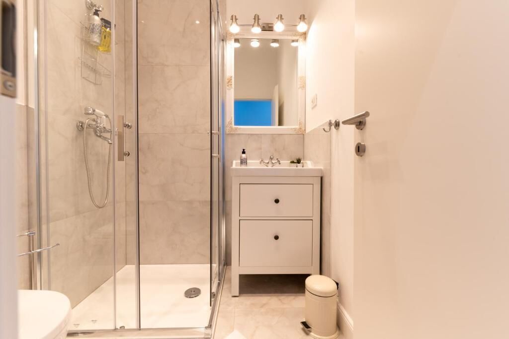 Ein modernes Badezimmer mit Duschkabine aus Glas, einem Waschbecken mit Spiegel darüber und einer Toilette.