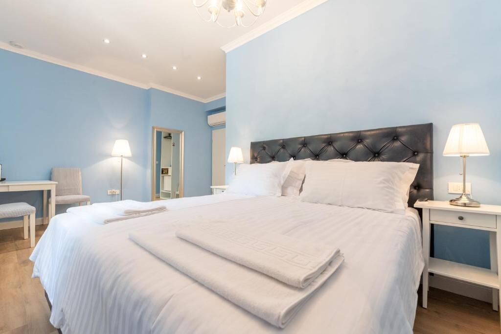 A bedroom with a large bed, bedside lamps, a chair, a desk, and a mirror.