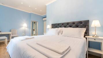 A bedroom with a large bed, bedside lamps, a chair, a desk, and a mirror.