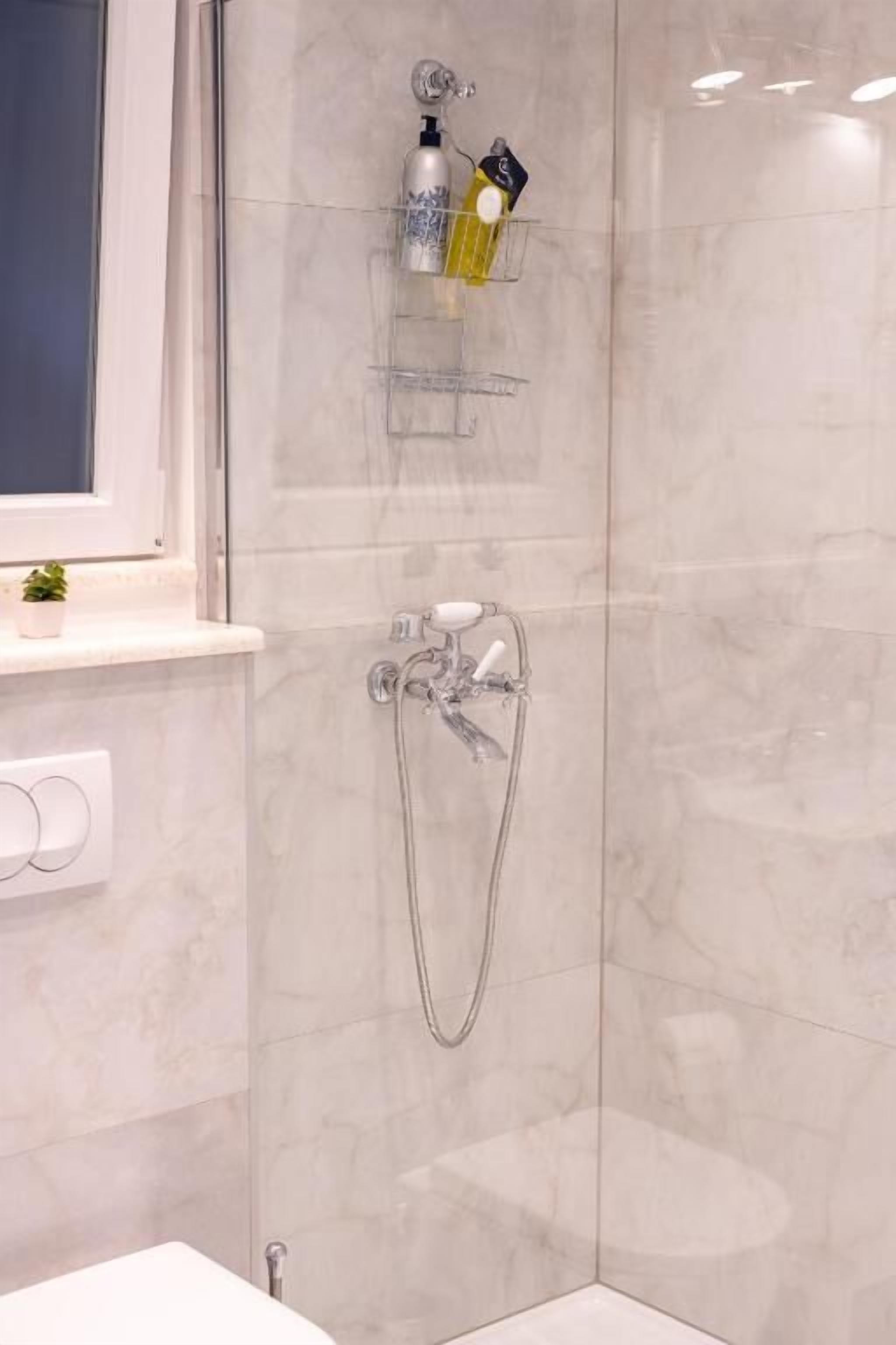 Un baño con ducha, lavamanos y ventana.