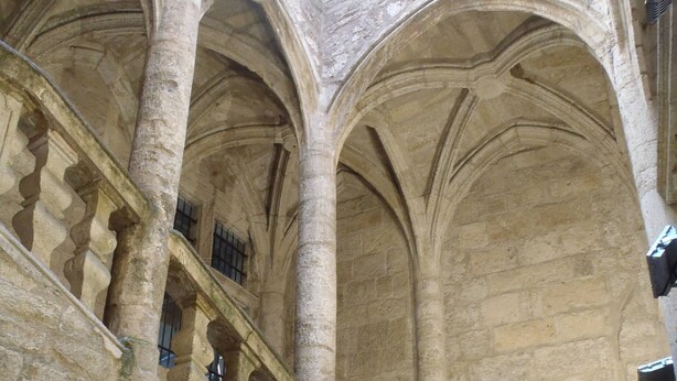 A stone staircase with a balustrade leading to an upper level with arched ceilings.