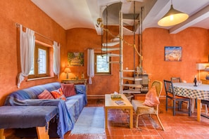 A cozy room with a sofa, a dining table, and a chair. There is a window with curtains, a lamp, and a painting on the wall. - Eco-friendly Gîte with Private Pool, Terrace and Wi-Fi in Autignac (Autignac)