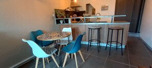 Une cuisine compacte avec un coin repas, comprenant une table avec des chaises, un comptoir-bar et des tabourets.
