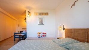 A bedroom with a bed, a desk, a chair, and a wall-mounted lamp.