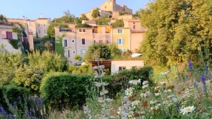 A garden with various flowers and a building in the background.