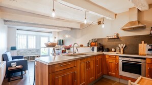 A modern kitchen with wooden cabinets, a stainless steel oven, and a large island with a sink.
