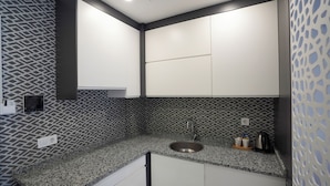 Cozinha moderna com bancada de granito, pia de aço inoxidável e painel decorativo atrás do fogão.