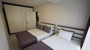 Quarto de hotel com duas camas, um guarda-roupa e um banheiro visível por uma porta aberta.