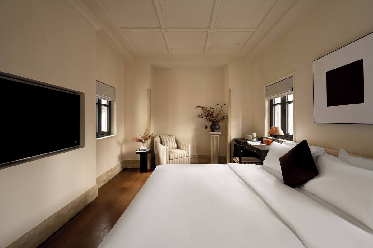 Habitación de hotel con una cama grande, una silla, un escritorio y un televisor.