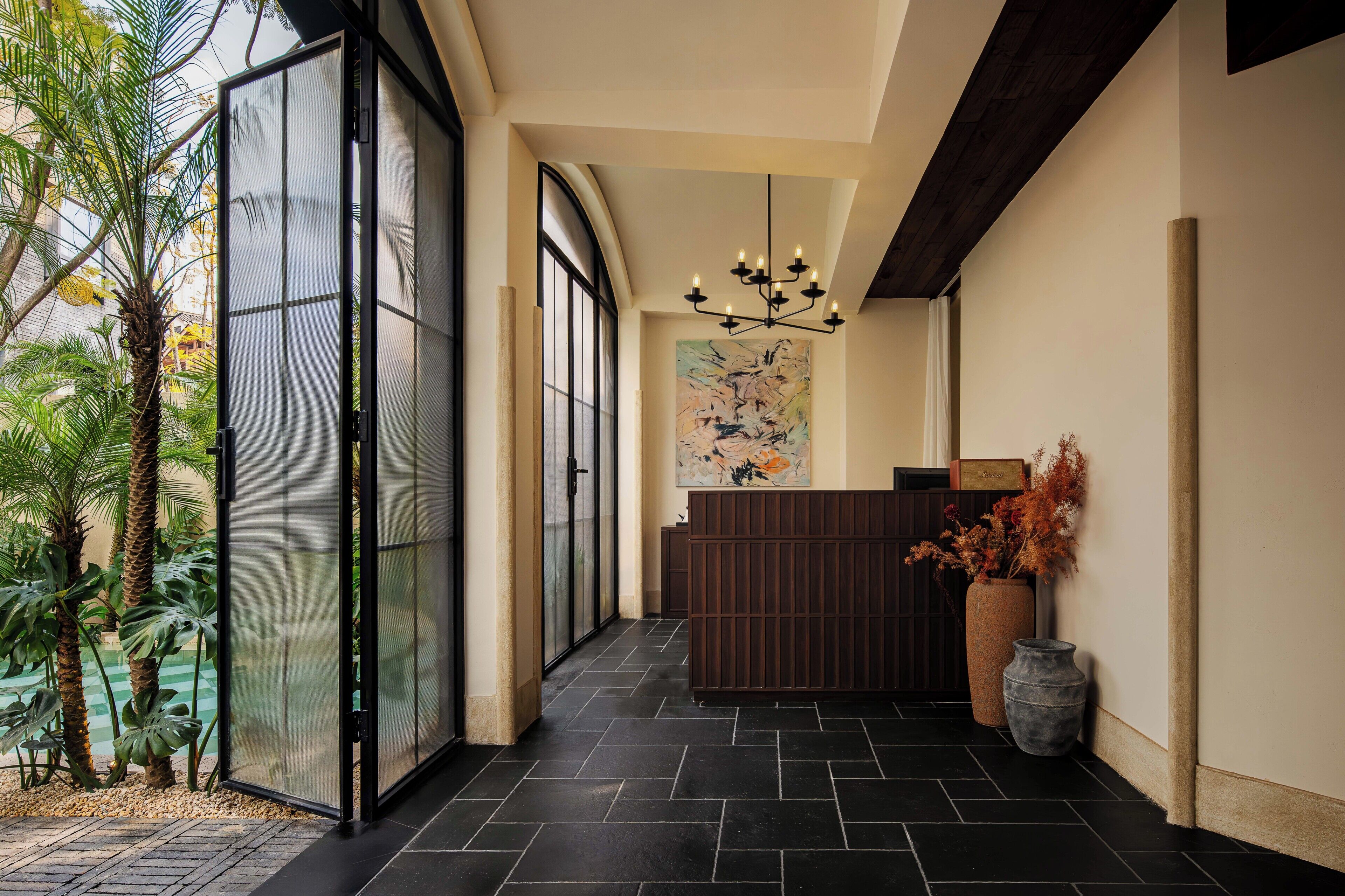 A reception area with a modern design, including a reception desk, a large abstract painting, and a potted plant.