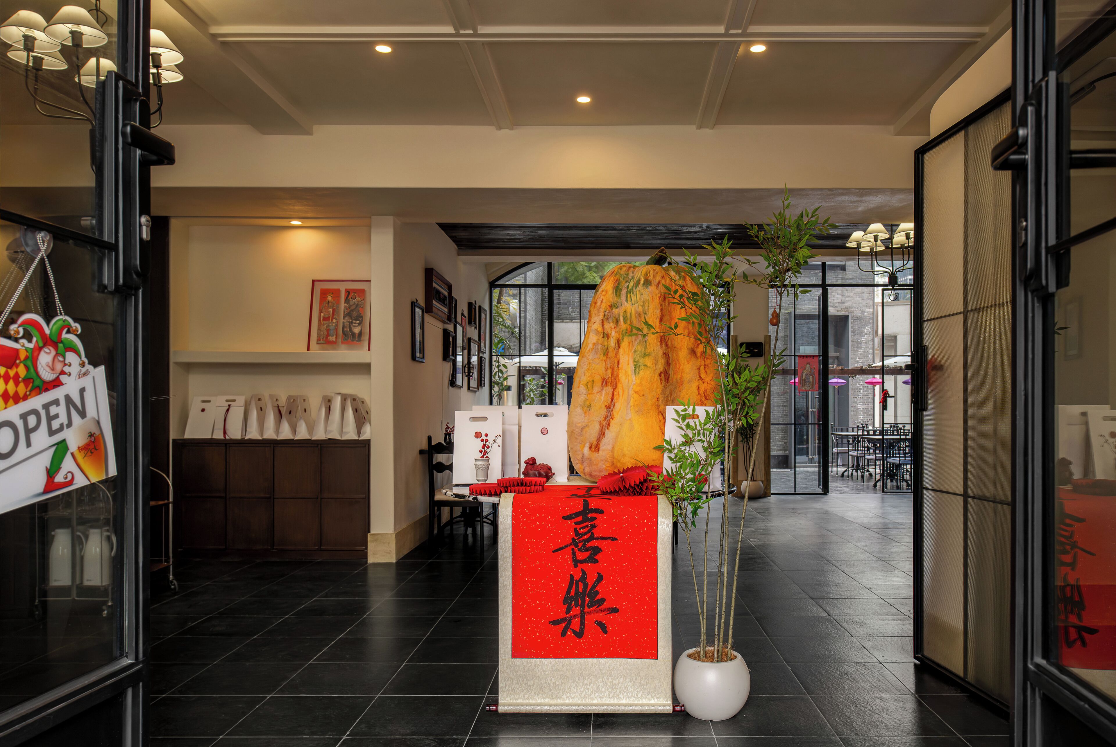 A hotel lobby with a reception desk, a large hanging sculpture, and a red banner with Chinese characters.