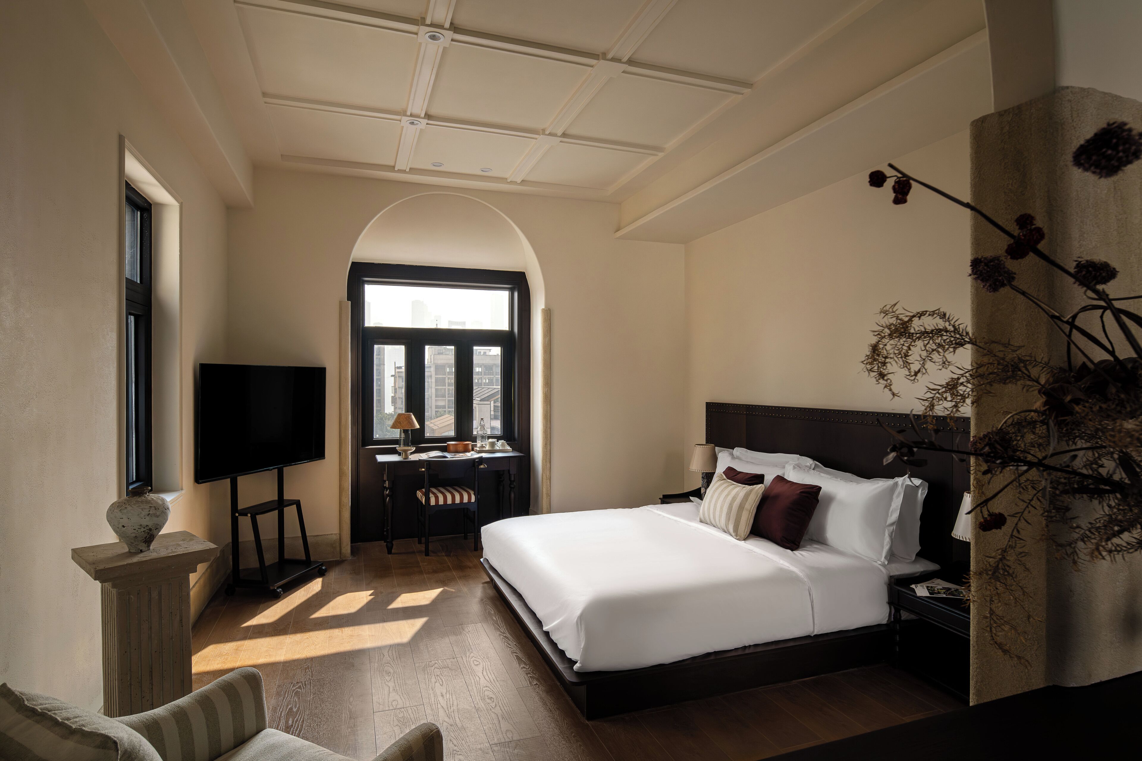 Une chambre d’hôtel avec un grand lit, un bureau avec une chaise, une télévision et une fenêtre donnant sur un beau paysage.