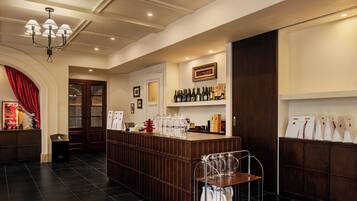 A bar area with a wooden counter, shelves with bottles, a chandelier, and a door with glass panels.