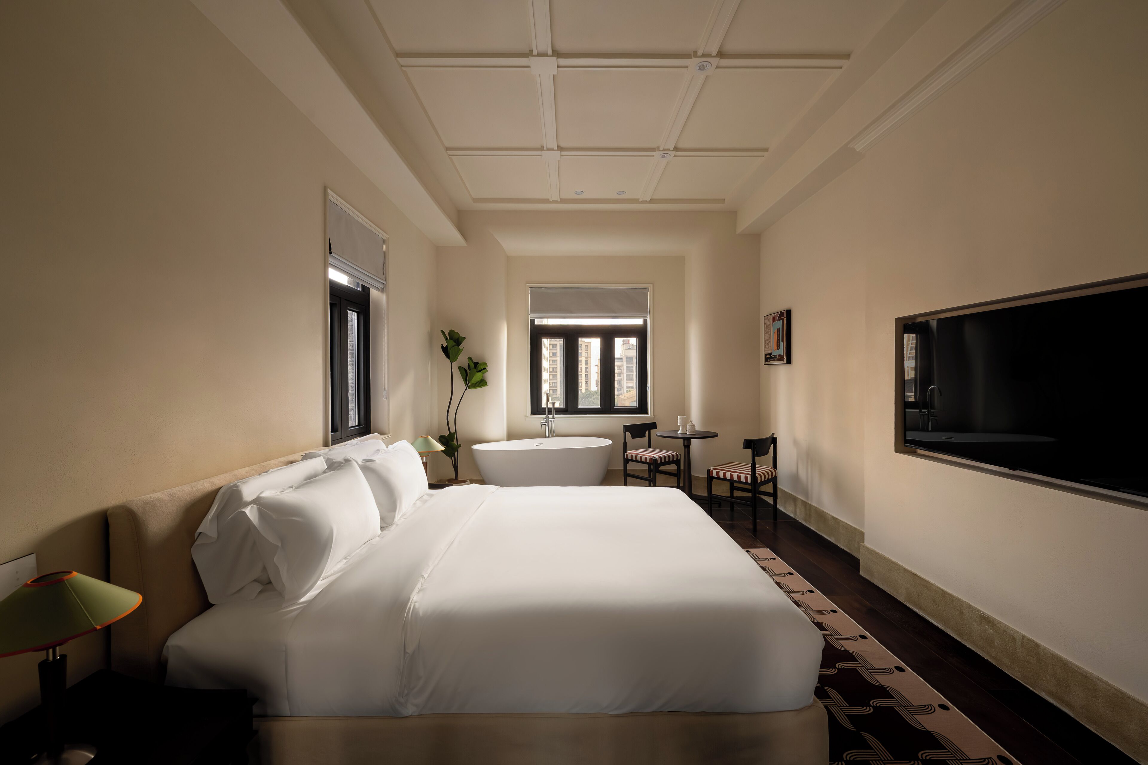 Une chambre d’hôtel avec un grand lit, une baignoire, une télévision et une petite table avec des chaises.