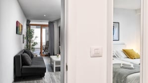 A modern hotel room with a sofa, a small table, and a bed with a yellow pillow. - Apartment 'Cerca Nueva B1' with Sea View, Wi-Fi and Air Conditioning (El Paraíso)