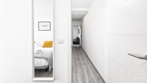 Ein Flur, der in ein Schlafzimmer mit Bett, einem gerahmten Bild und einer Tür führt.