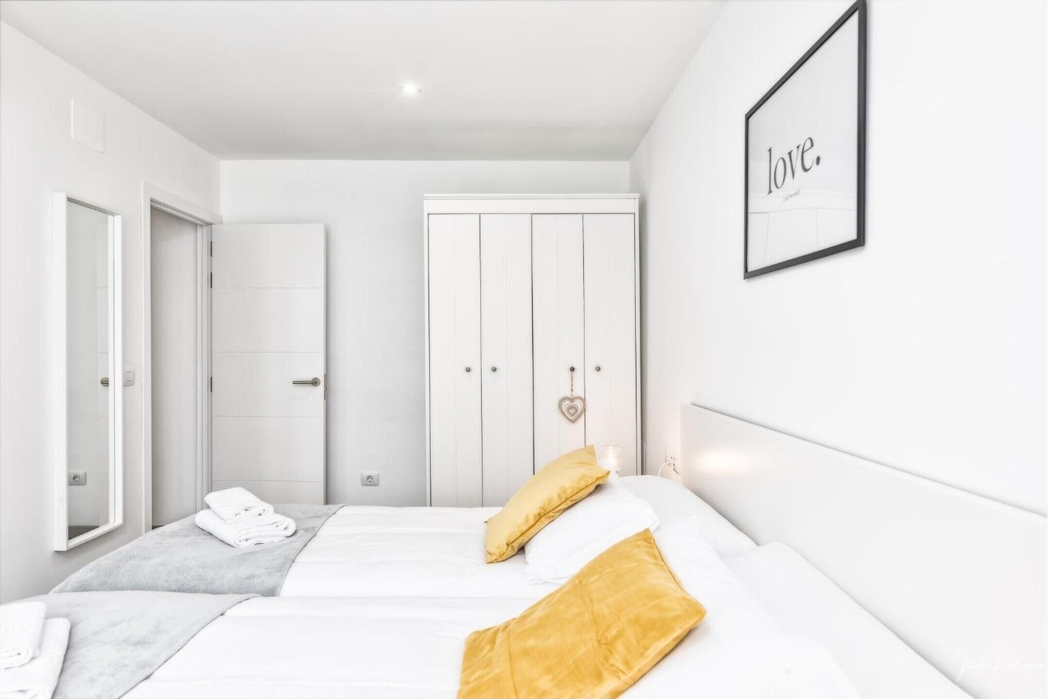 Une chambre d’hôtel avec un lit, une armoire, un miroir et un mot encadré accroché au mur.