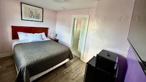 A hotel room with a bed, bedside table, lamp, and a wardrobe. - OSHAWA INN MOTEL (Oshawa)