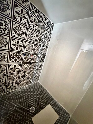 A bathroom with a tiled wall featuring geometric patterns and a hexagonal floor design. - OSHAWA INN MOTEL (Oshawa)