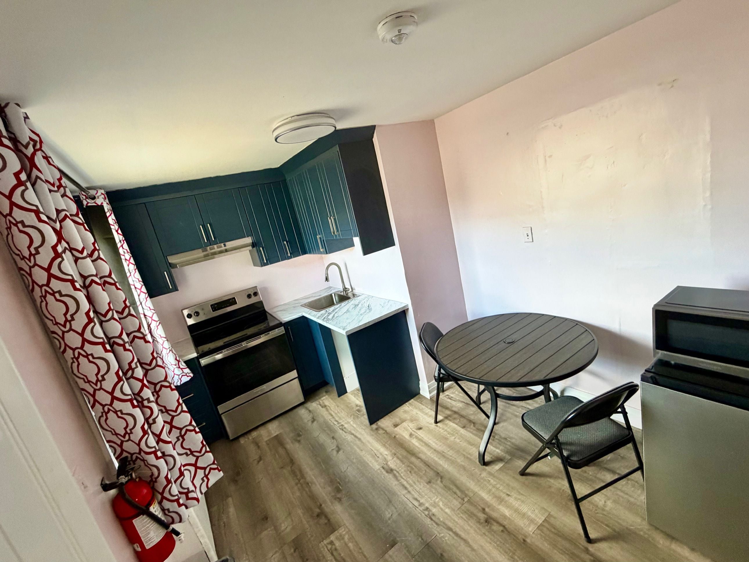 Une cuisine compacte avec un coin repas comprenant une table et des chaises, ainsi qu’un four encastré.