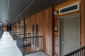 Un couloir aux murs lambrés, avec des rampes en métal et des portes numérotées 409 et 411.