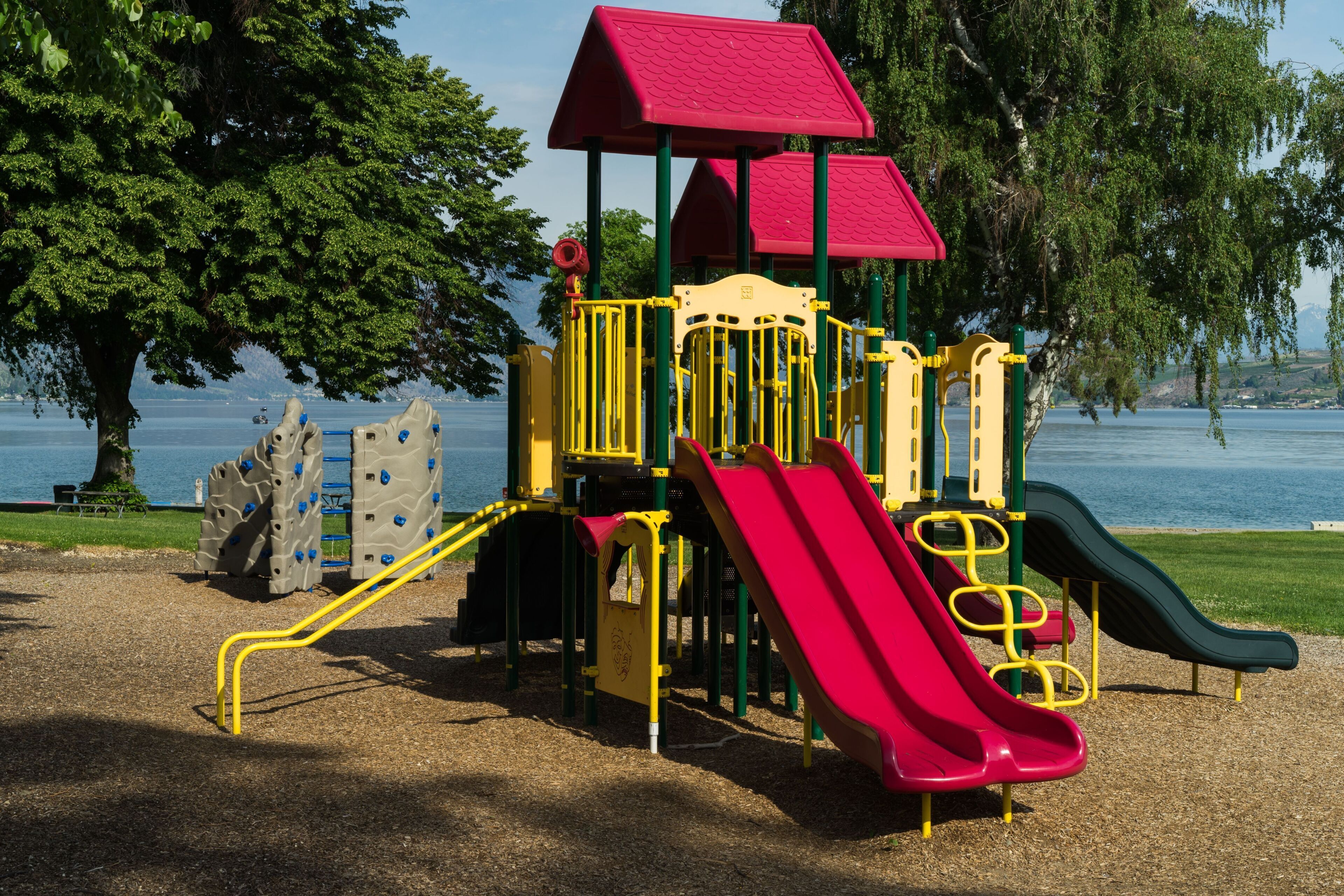 Ein Spielplatz mit Rutschen und Klettergerüsten in der Nähe eines Gewässers.