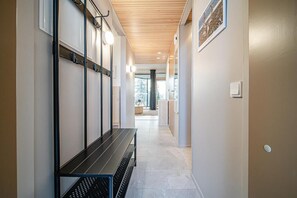 A hallway with a bench, coat hooks, and a picture on the wall. - Gielas Joiku Chalet - Ski-in Ski-out & Mountain View (Kittilä)