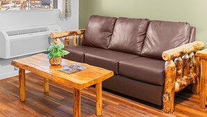 Un canapé en cuir marron, une table basse en bois agrémentée d’une plante, et une chaise en bois au design original.