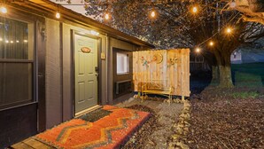 A wooden house with a door, a bench, and a tree. - Meadow View | King Suite for 2 | Wears Valley (Sevierville)